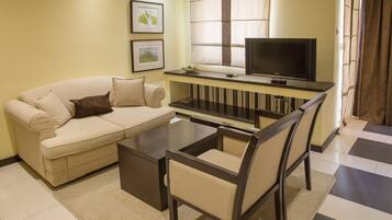A living room with a sofa, coffee table, TV, and chairs.
