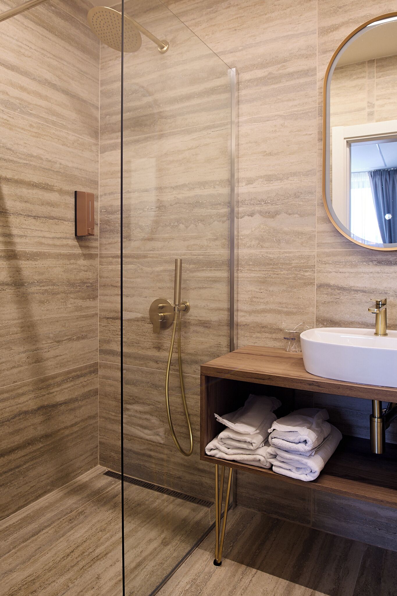 A modern bathroom with a glass-enclosed shower, a wooden vanity with a sink, and a mirror.