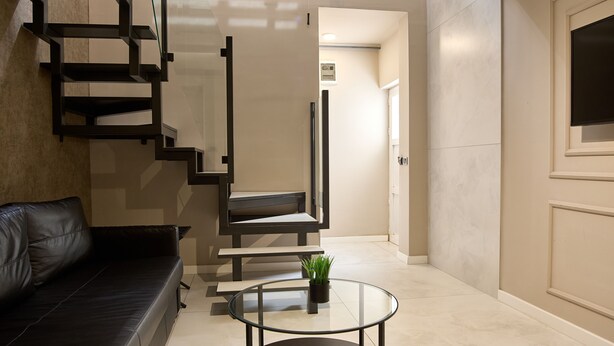 Ein modernes Wohnzimmer mit einer schwarzen Ledersofa, einem Glastisch und einer Treppe im minimalistischen Stil.