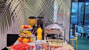 Ein Buffet mit verschiedenen Speisen und einer Wand mit tropischem Blattmuster.