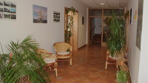 A hallway with wicker chairs, potted plants, and a staircase leading to another room. - Garni Hotel Villa Tamara (Moravske Toplice)