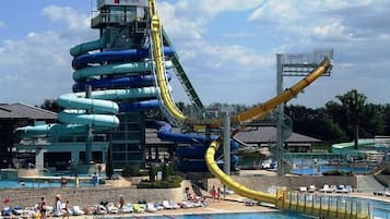Parque acuático con múltiples toboganes y zona de piscina con sillones y sombrillas.