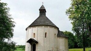A small, white, round church with a conical roof and a cross on top, surrounded by greenery. - Garni Hotel Villa Tamara (Moravske Toplice)