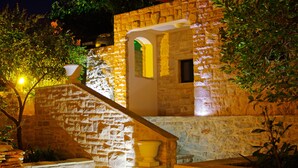 Un edificio de piedra con una escalera que conduce a la entrada, rodeado de follaje.
