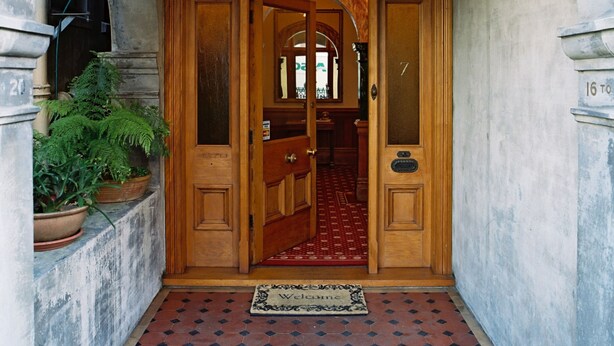 A grand entrance with a tiled floor, a wooden door, and a welcoming mat. - Braemar on Parliament Street (Auckland)