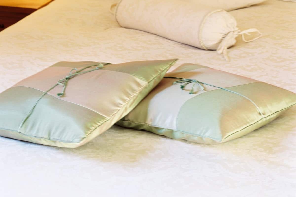 A neatly made bed with pillows and a lamp on a bedside table.