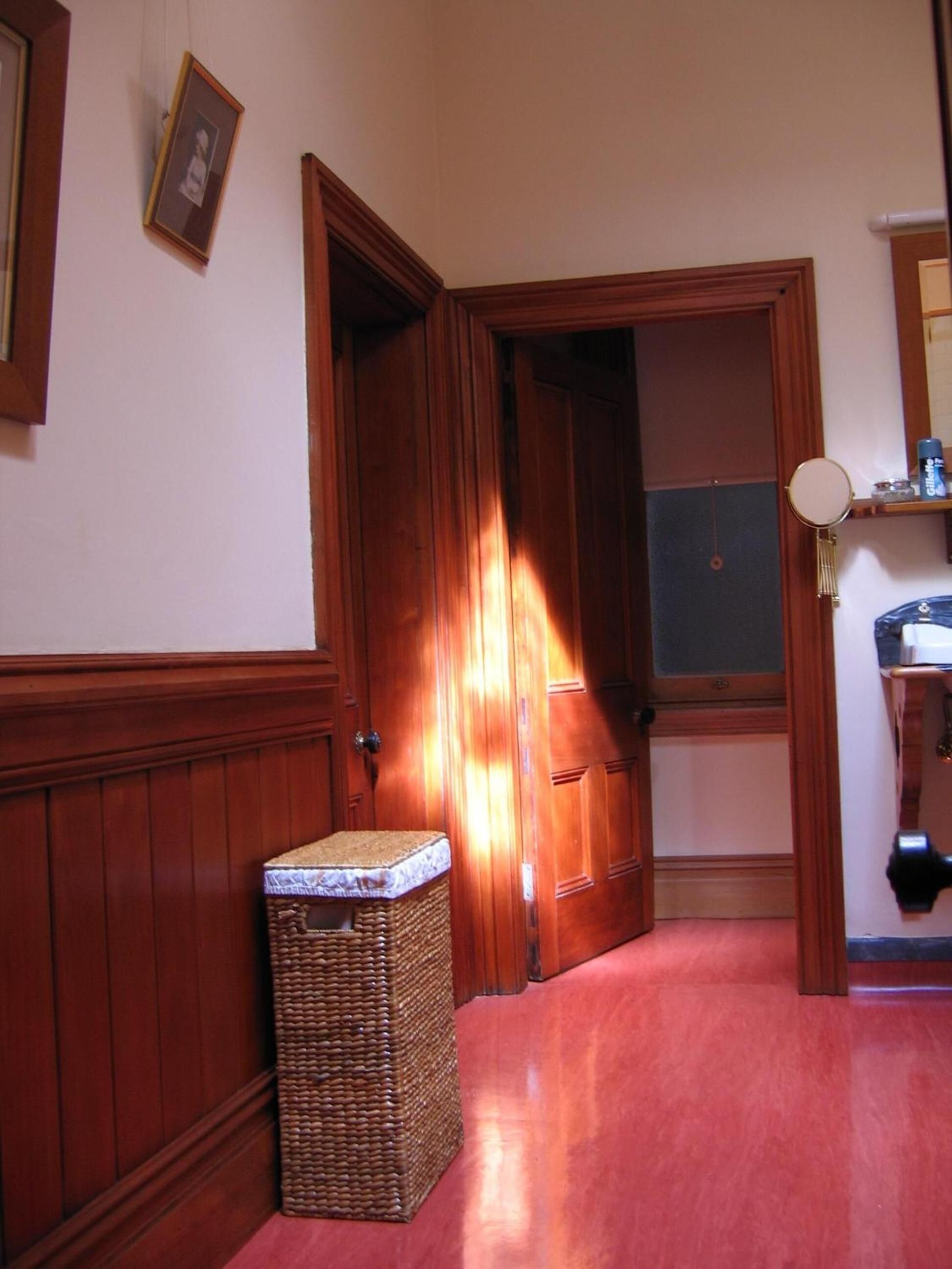 Un passadís amb portes de fusta, una cistella de vimet i un mirall a la paret.