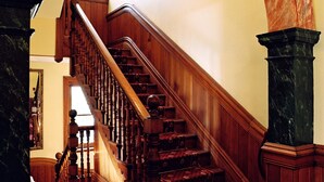A grand staircase with a wooden handrail and carpeted steps, leading to an upper floor. - Braemar on Parliament Street (Auckland)