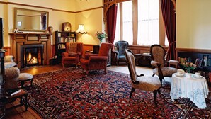 A traditional room with a fireplace, a chandelier, and a large window with curtains. - Braemar on Parliament Street (Auckland)