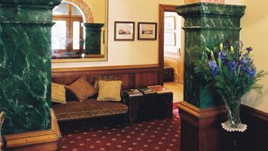 A lobby with a marble archway, a sofa, a coffee table, and a vase with flowers. - Braemar on Parliament Street (Auckland)
