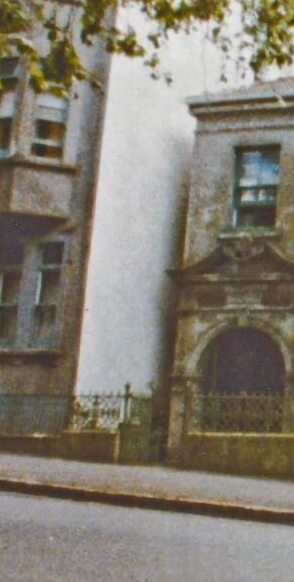 Un edificio histórico con una entrada arqueada destacada y un balcón.
