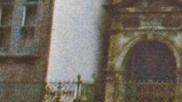 Een historisch gebouw met een opvallende bogenpoort en een balkon.