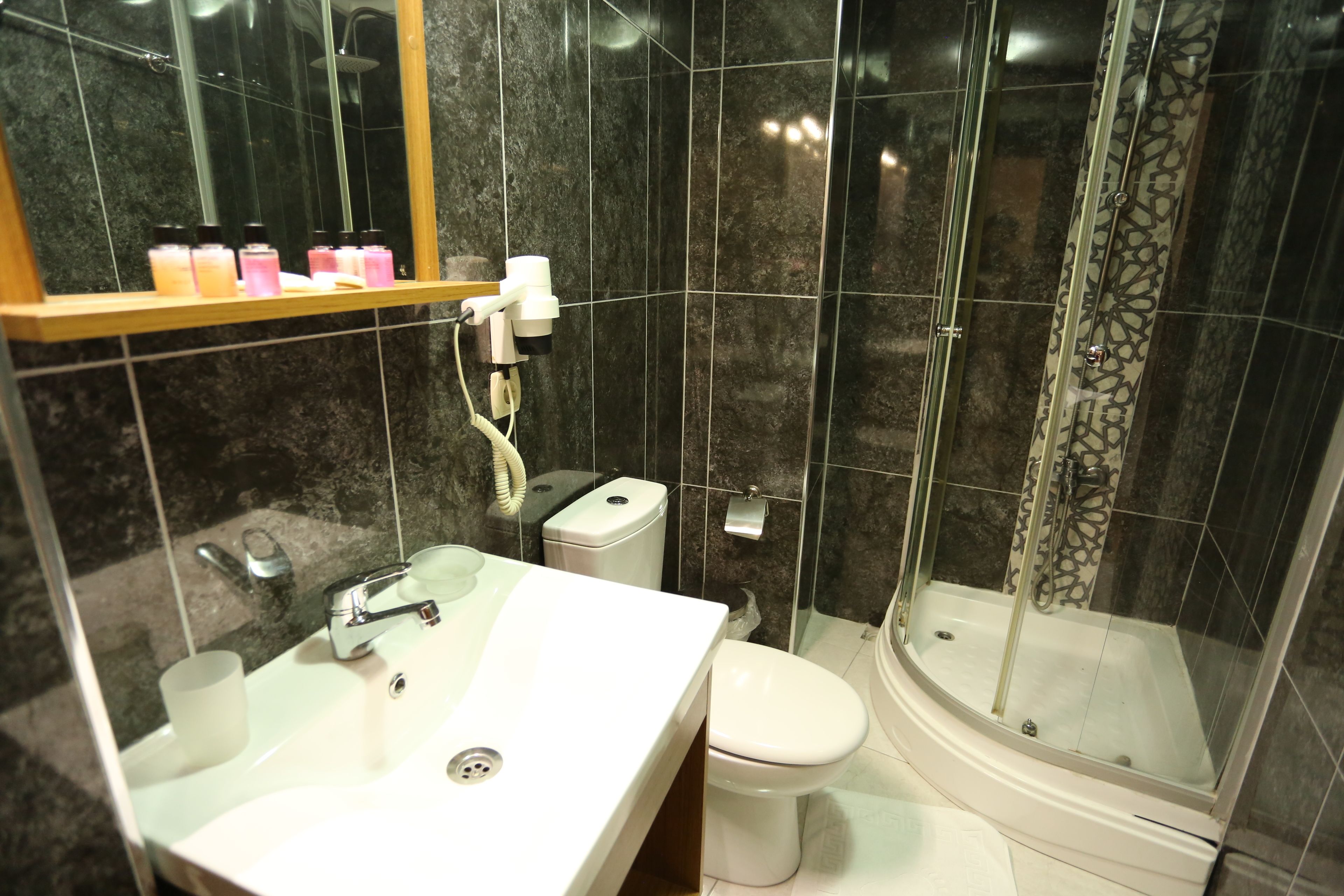A bathroom with a white sink, toilet, and glass-enclosed shower.