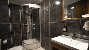 Un bagno moderno con cabina doccia in vetro, lavandino bianco e water.