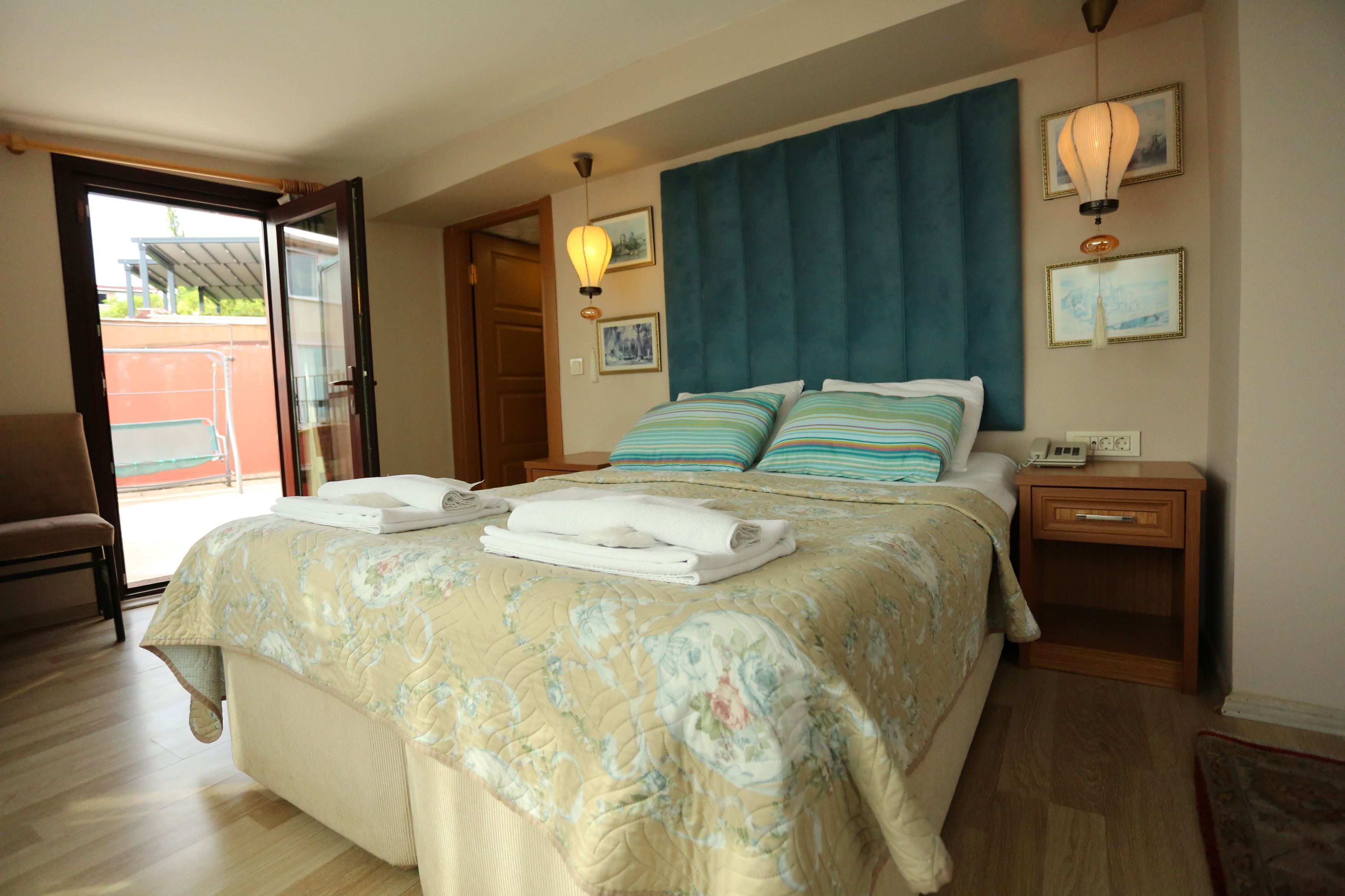 Una habitación de hotel con cama, mesita de noche, una silla y una puerta que da a un espacio exterior.