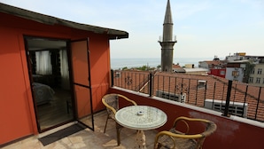 Un balcone con tavolo e sedie, vista sul mare e una moschea all'orizzonte.