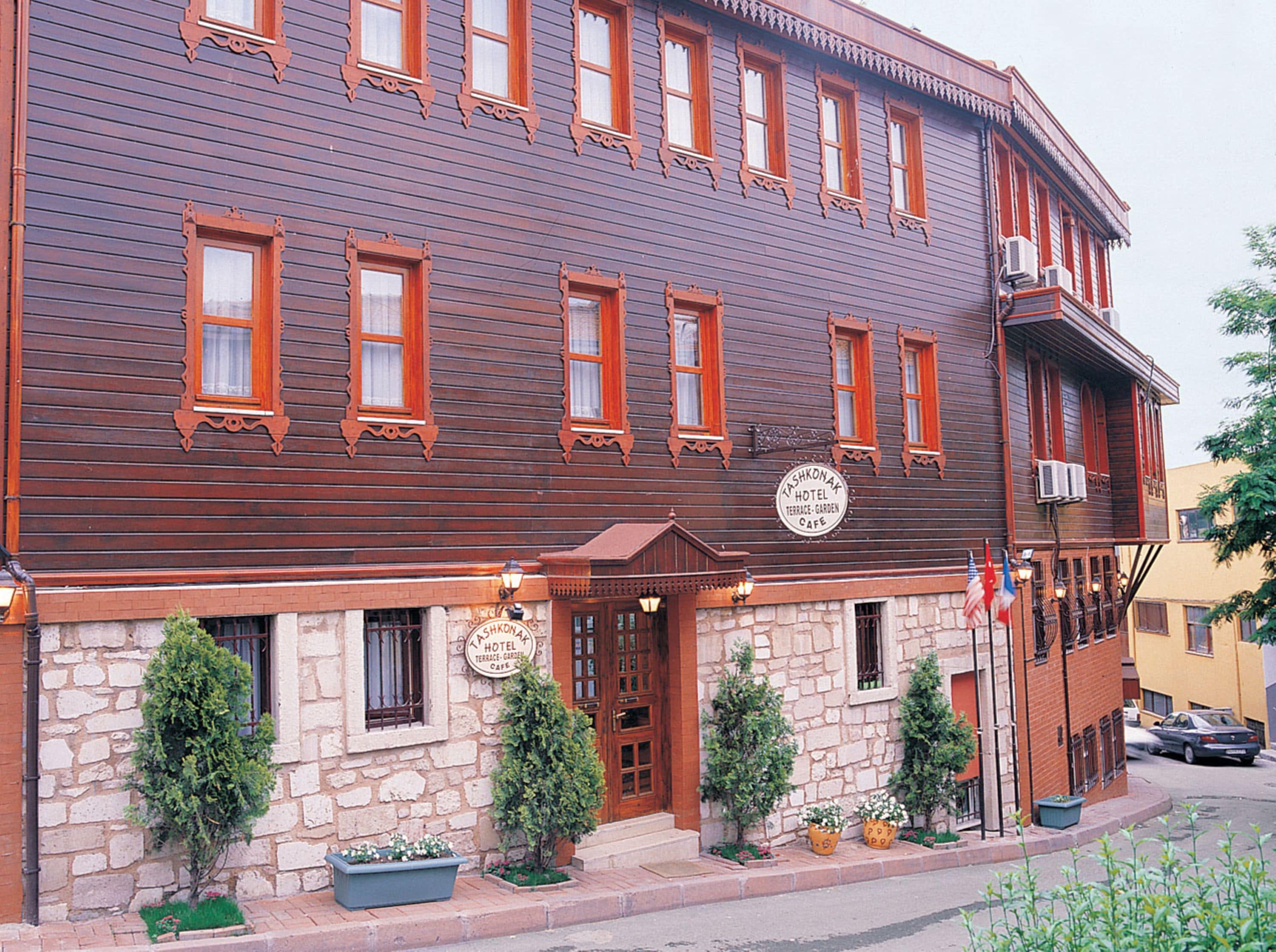 A two-story hotel with a stone facade, multiple windows with ornate wood trim, and a sign indicating it is a hotel and cafe.