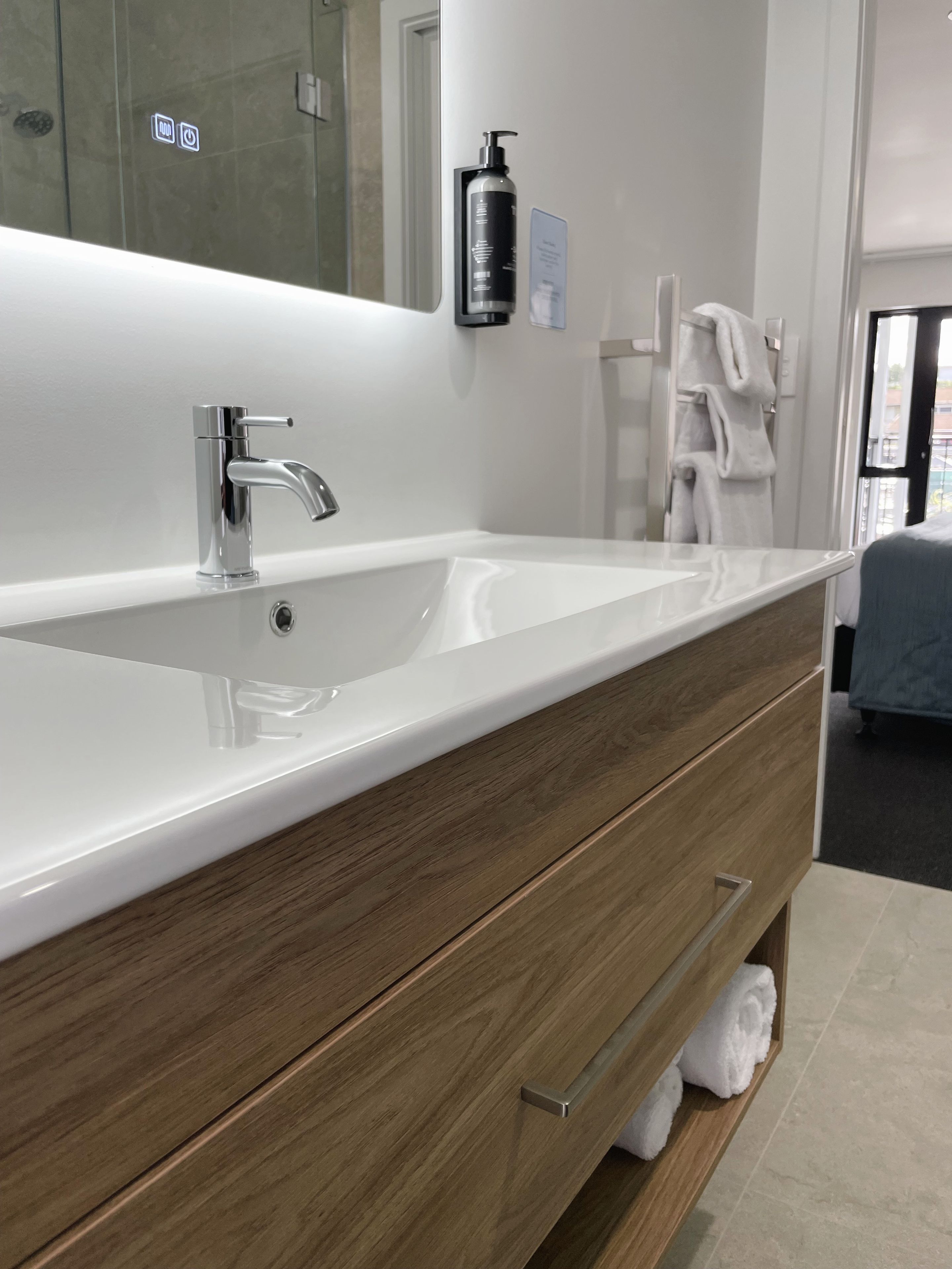 A modern bathroom with a large white sink, a mirror, and a wooden vanity with drawers.