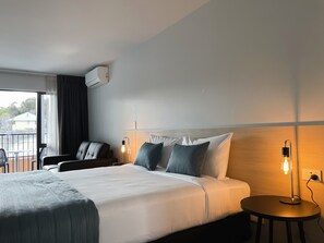 A hotel room with a bed, a chair, a small table, and a view of the outdoors. - Clearbrook Motels Wanaka (Wanaka)