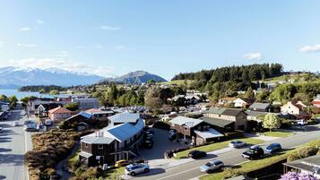 A town with a mix of residential and commercial buildings, a parking lot, and a view of mountains in the background.