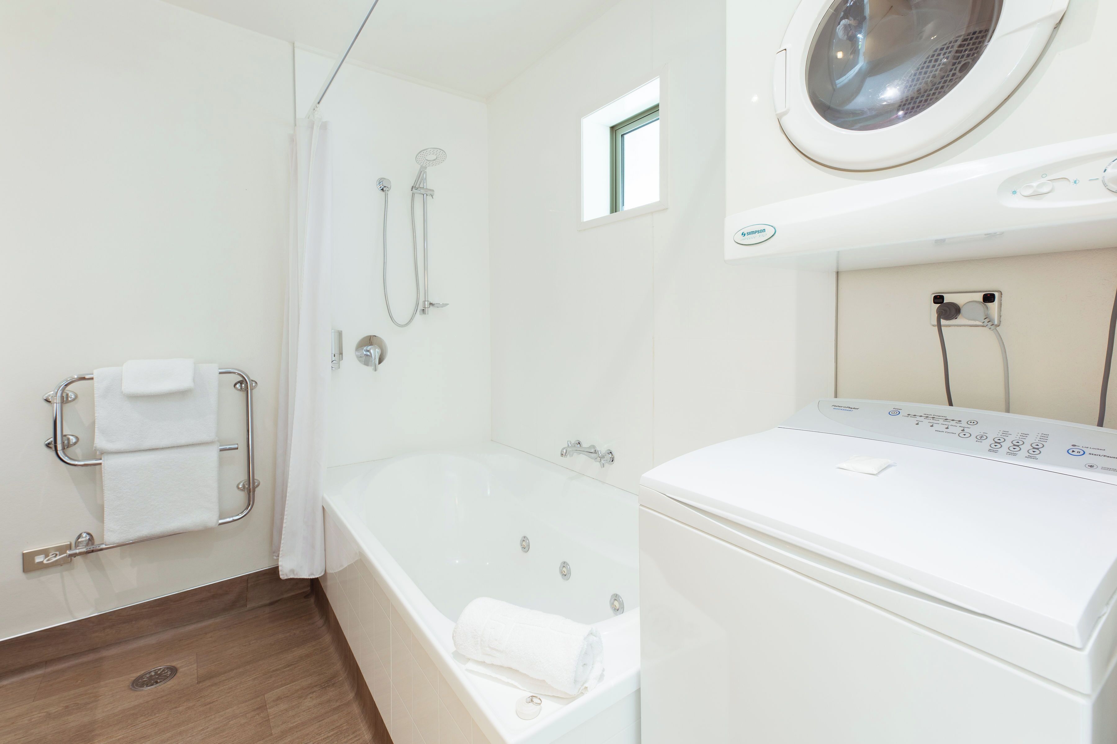 Ett badrum med badkar, dusch och en tvättmaskin med frontmatning.