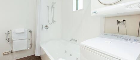 Ett badrum med badkar, dusch och en tvättmaskin med frontmatning.