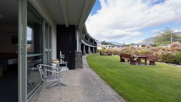 A modern building with a covered outdoor seating area, a well-maintained lawn, and a view of the surrounding landscape.