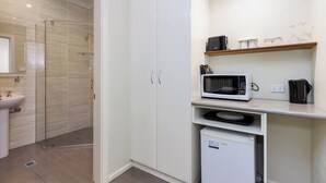 Un baño moderno con cabina de ducha de vidrio, un lavamanos y un refrigerador compacto.