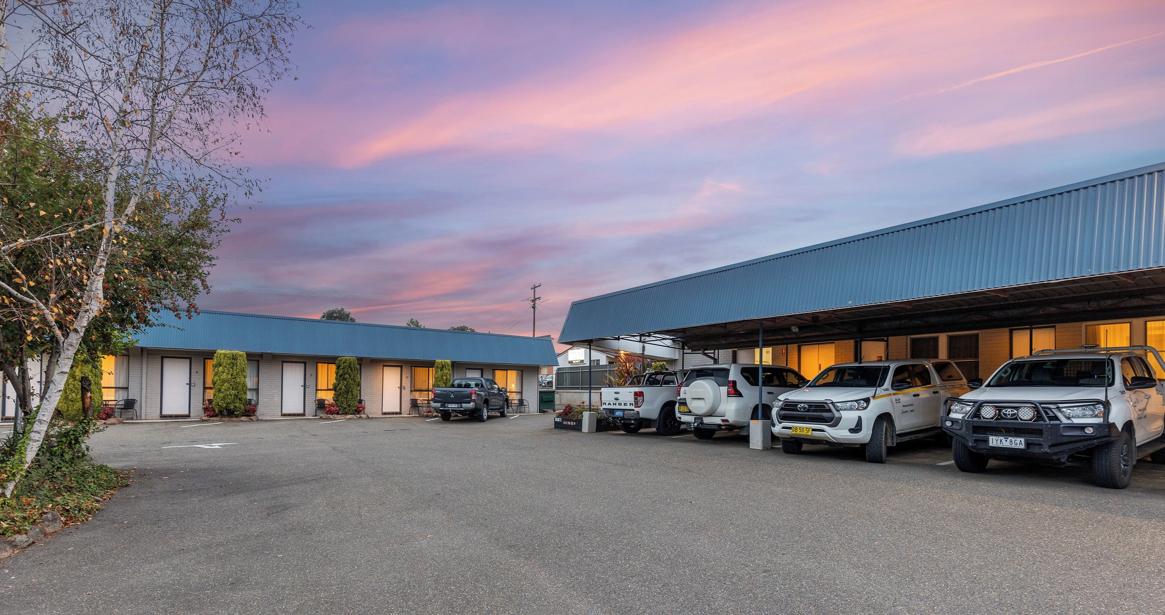 A parking lot with several SUVs and a building with a blue roof.