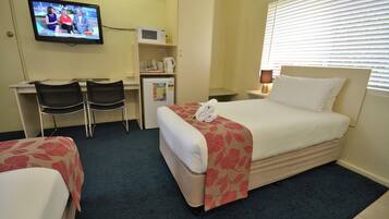 A hotel room with a bed, a desk with two chairs, a television, a microwave, and a refrigerator.