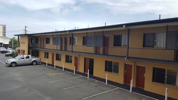 A motel with a two-story structure, a parking lot, and a white pickup truck parked in front.