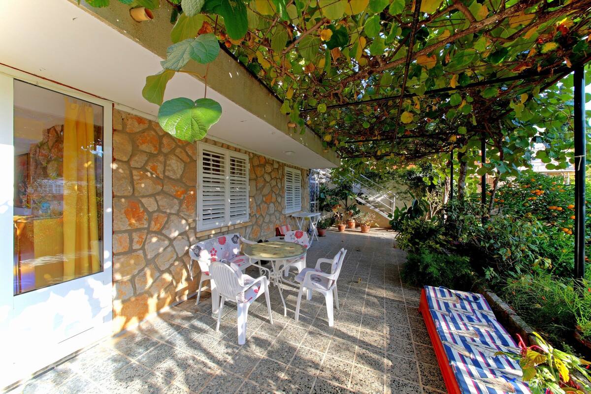 A patio with a stone wall, white shutters, and a table with chairs.