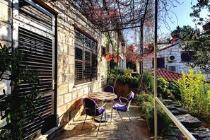 Une cour avec une table et des chaises, un escalier et un mur en pierre.