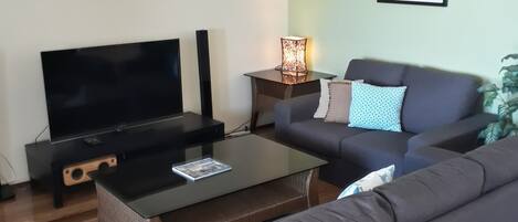 Ein Wohnzimmer mit Flachbildfernseher, einer Couch, einem Couchtisch und einem Deckenventilator.