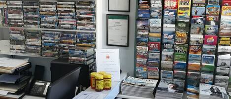 A bookstore with a wall clock, a visitor information sign, and various books and magazines on shelves.