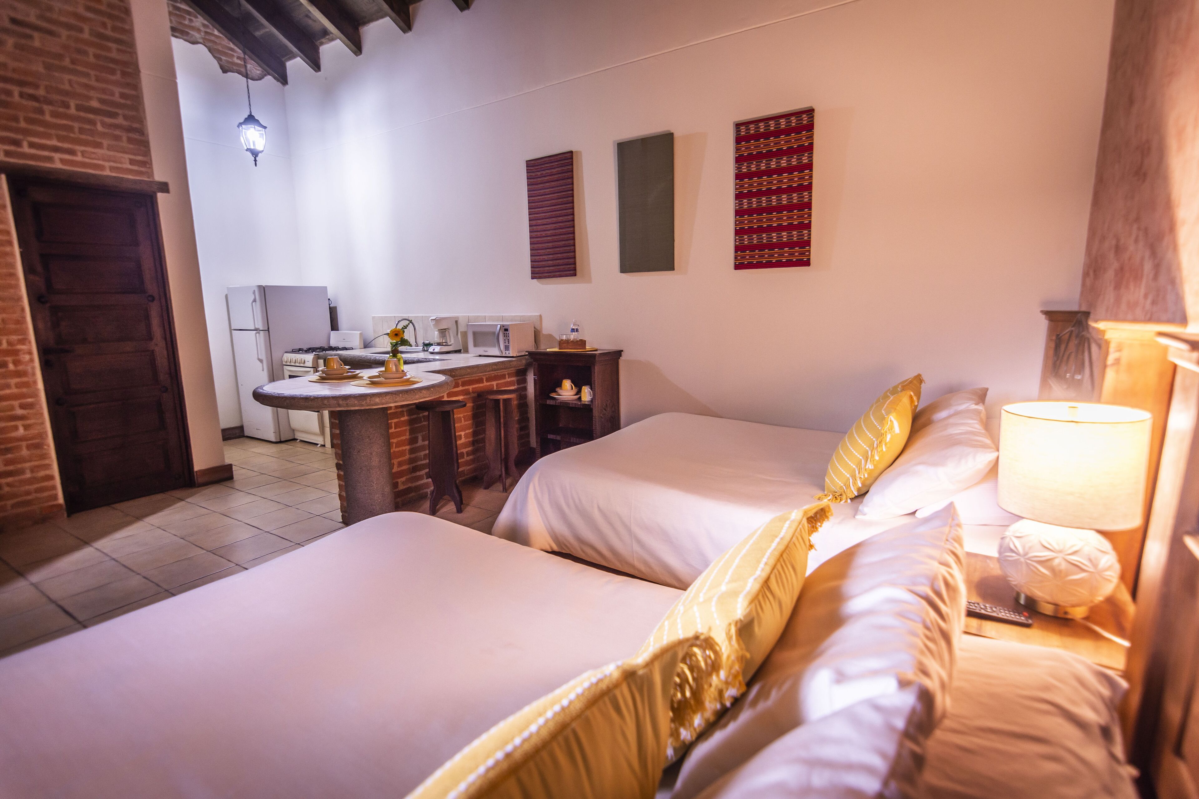 A hotel room with two beds, a dining table, a refrigerator, and a microwave.