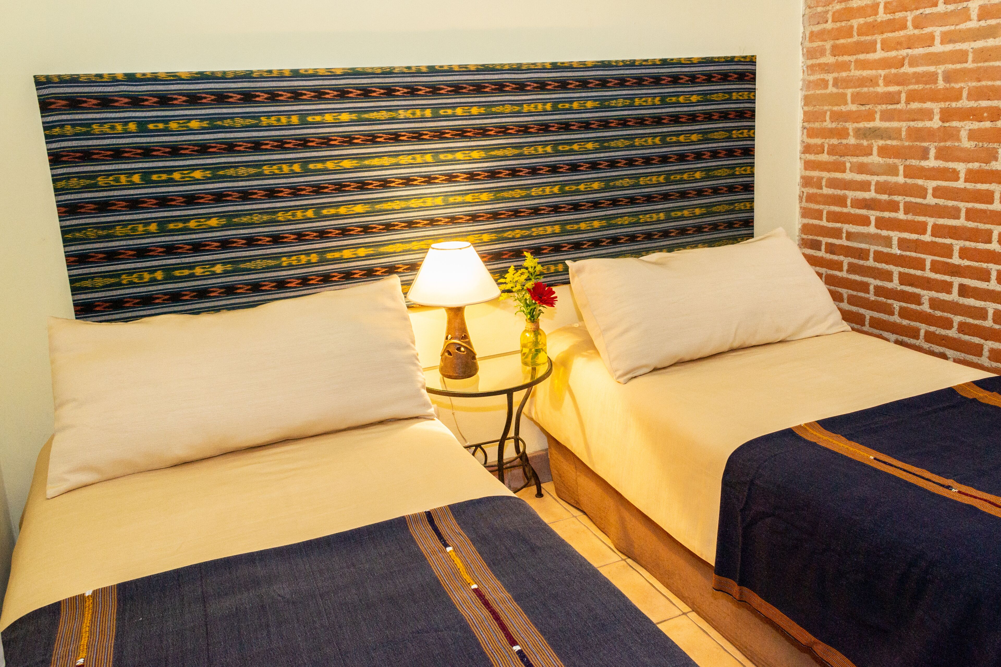 A hotel room with two beds, a lamp, and a vase with flowers.