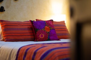Una cama con ropa de cama a rayas y almohadones florales de colores.