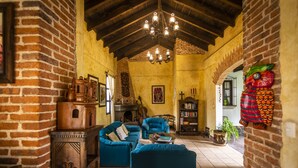 Un salon au style rustique, avec des murs en briques apparentes, des meubles en bois et un lustre.