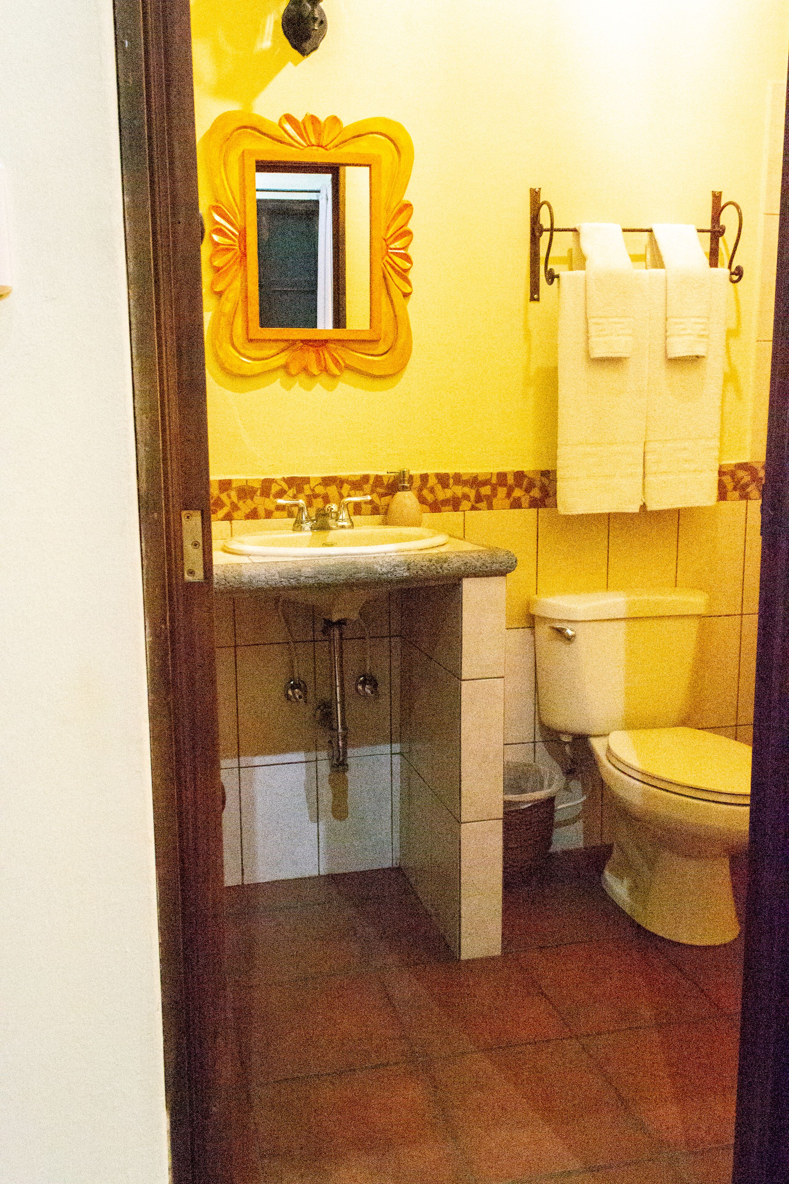 A bathroom with a sink, toilet, and a mirror with a decorative frame.
