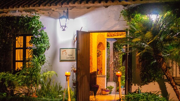 L’entrée d’un hôtel, avec une enseigne indiquant « Hôtel Las Marías », est entourée d’une végétation luxuriante et d’une arche en briques.
