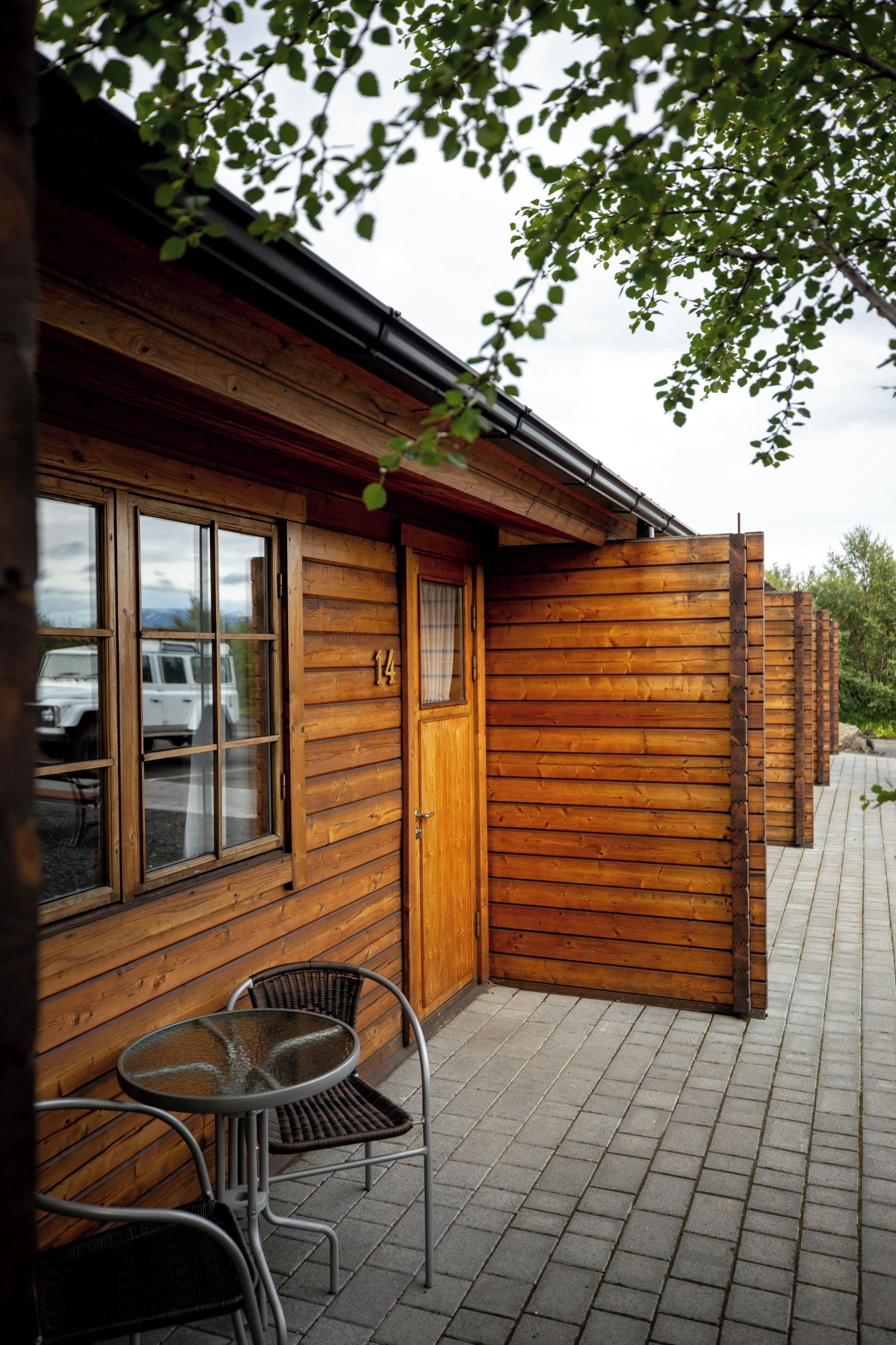 A wooden cabin with a window, a door, and a small outdoor seating area with a table and chairs.