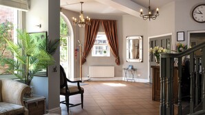A spacious room with a large window, a chandelier, and a view of the outside. - Fox & Hounds Country Hotel (Chulmleigh)