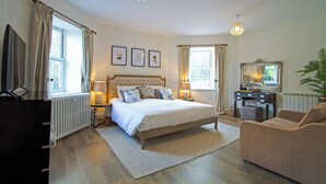 A bedroom with a bed, bedside lamps, a dresser, a chair, a desk, a mirror, and framed pictures on the wall. - Fox & Hounds Country Hotel (Chulmleigh)