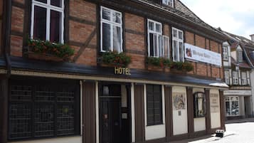 A traditional brick building with a sign reading "HOTEL" and a cobblestone street in front.