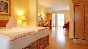 A hotel room with a large bed, a desk with a chair, a wardrobe, and a door leading to another room. - Weinhaus Wöhler (Schwerin)