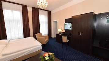 Ein Hotelzimmer mit Bett, Schreibtisch, Stuhl, Fernseher und Kleiderschrank.
