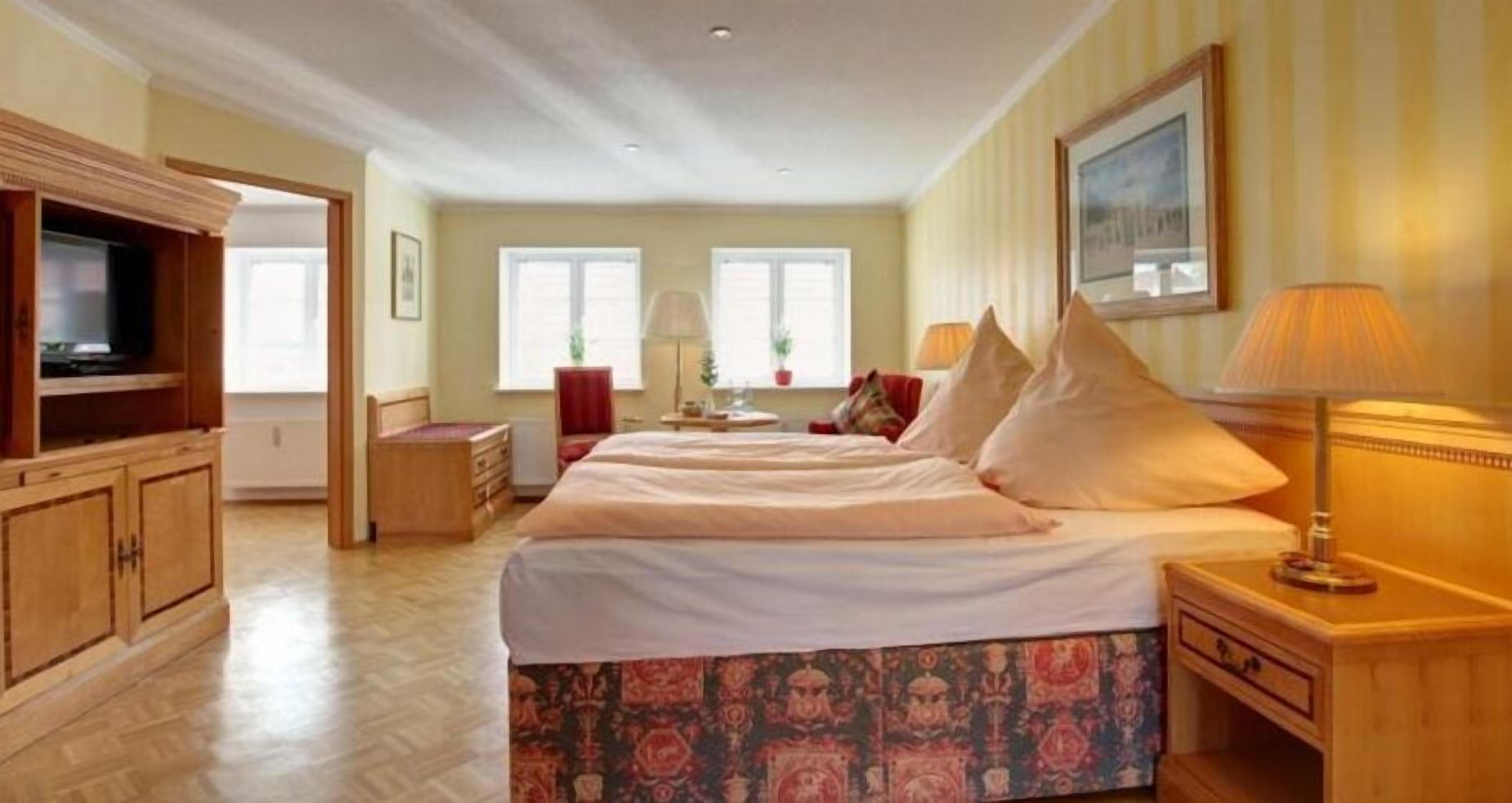 Ein Hotelzimmer mit einem großen Bett, einem Fernseher, einem Schreibtisch und einem Stuhl.