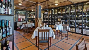 A wine cellar with wooden beams, shelves of wine bottles, and tables set for dining. - Weinhaus Wöhler (Schwerin)