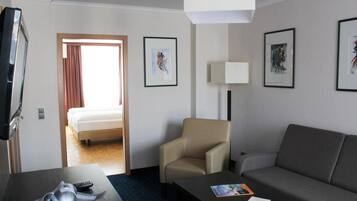 Une chambre d’hôtel comprenant un lit, un canapé, une chaise, un téléviseur et des œuvres d’art encadrées accrochées aux murs.